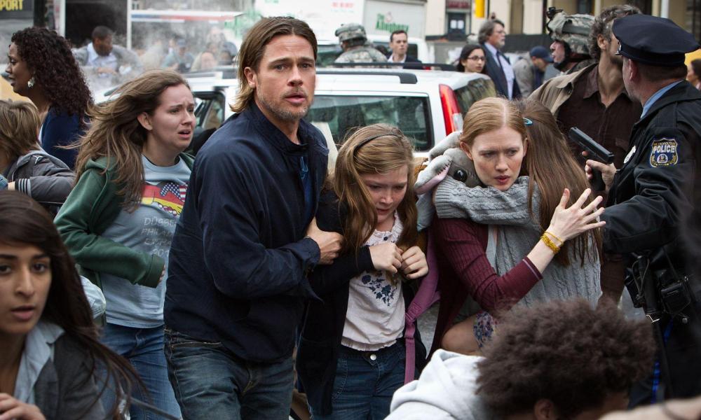 Brad Pitt holds a young girl as he walks through the streets.