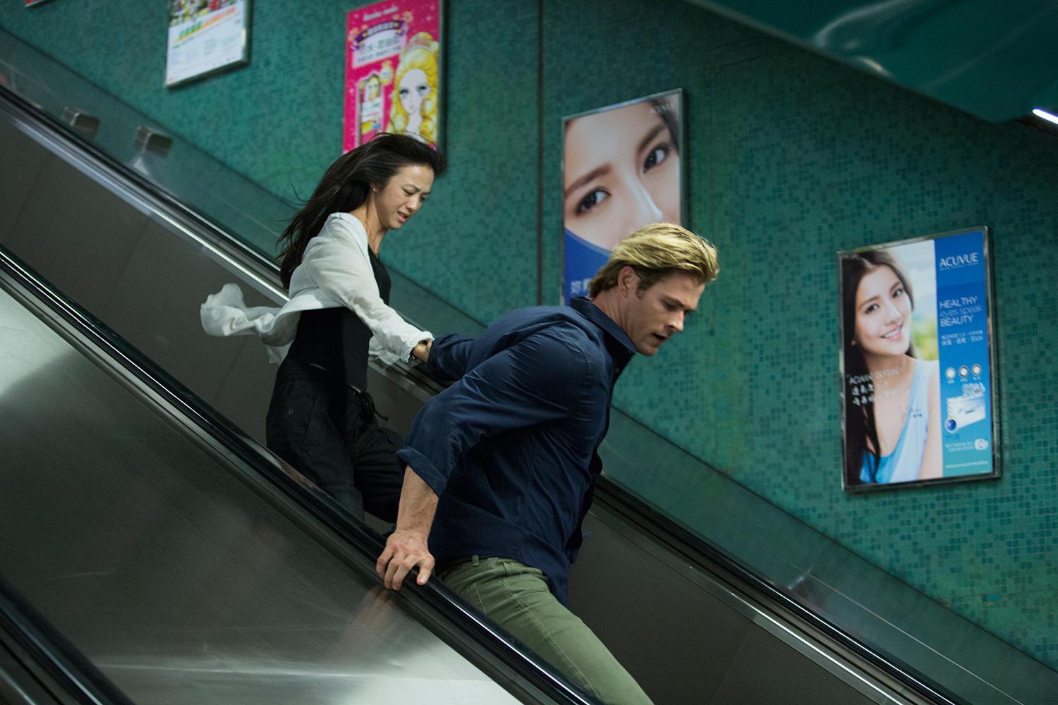 Um homem e uma mulher descem escadas correndo em Blackhat.