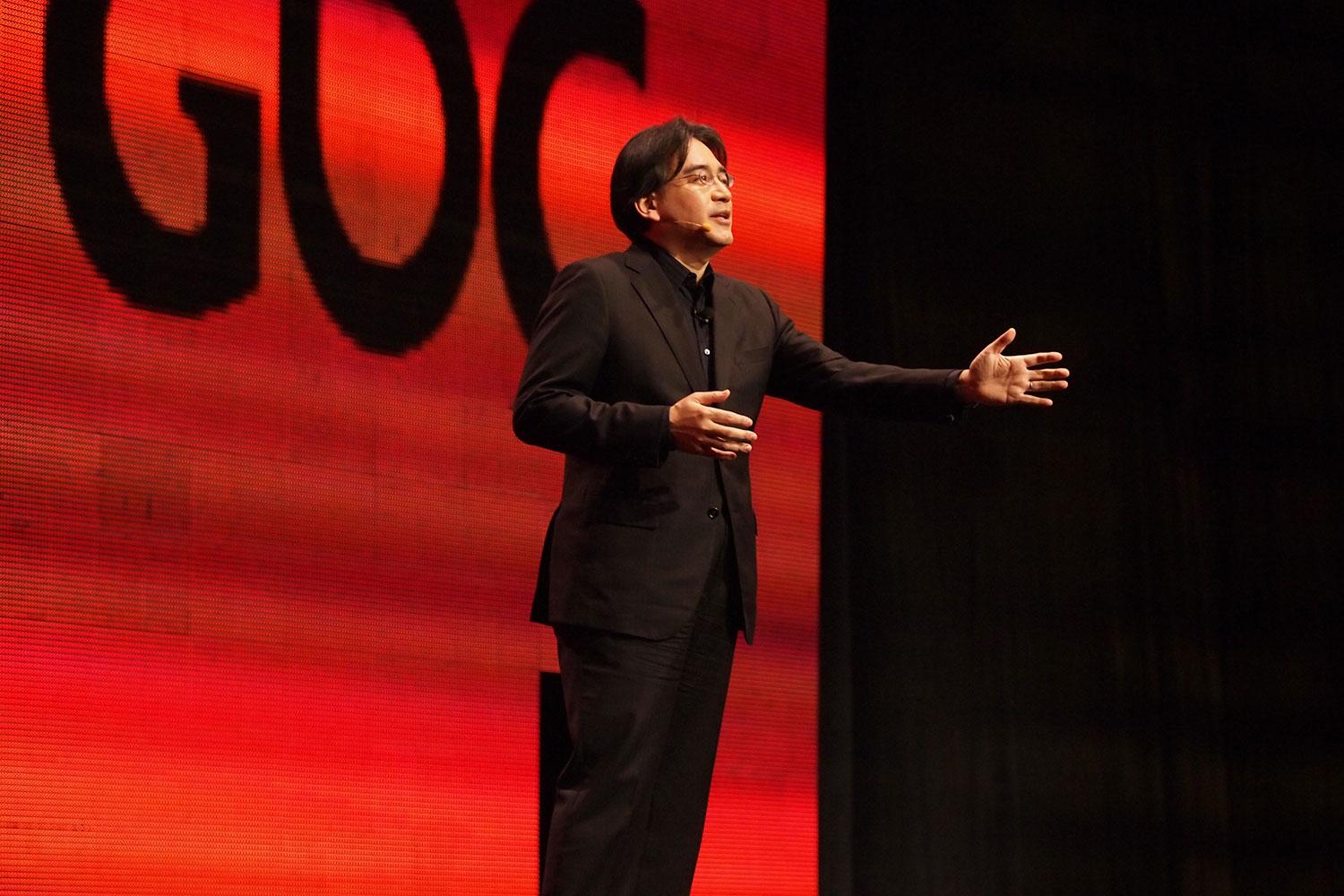 Satoru Iwata en la GDC de 2011 frente a un logotipo rojo de la GDC.