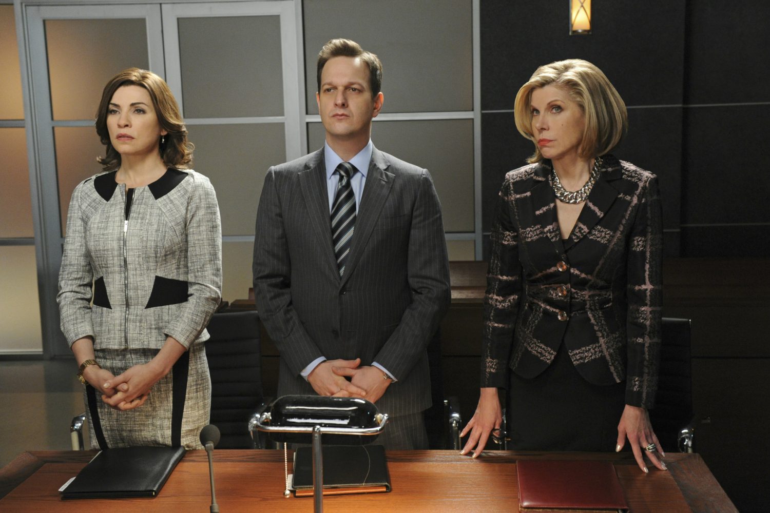 Three lawyers stand beside each othe behind a table.