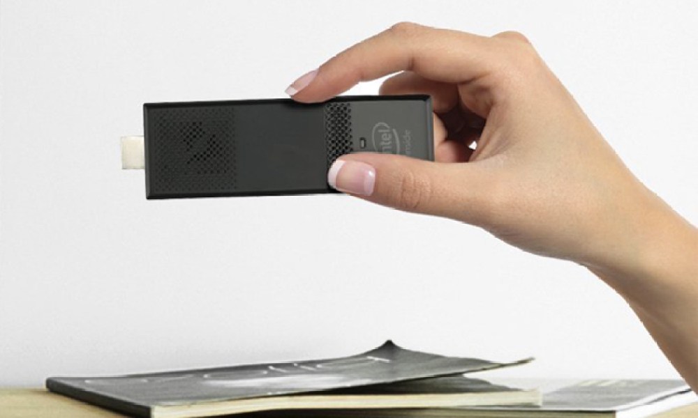 A person holding an Intel Compute Stick above a desk.