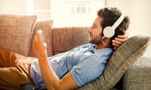 aftermaster pro fixes tv movie audio issues man on couch watches a mobile phone