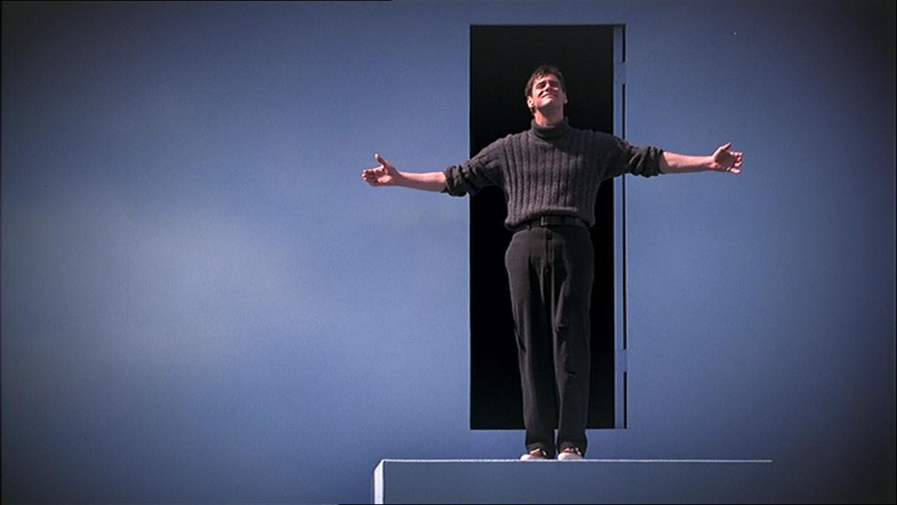 Jim Carrey dans le rôle de Truman Burbank écartant les bras et levant les yeux dans The Truman Show.