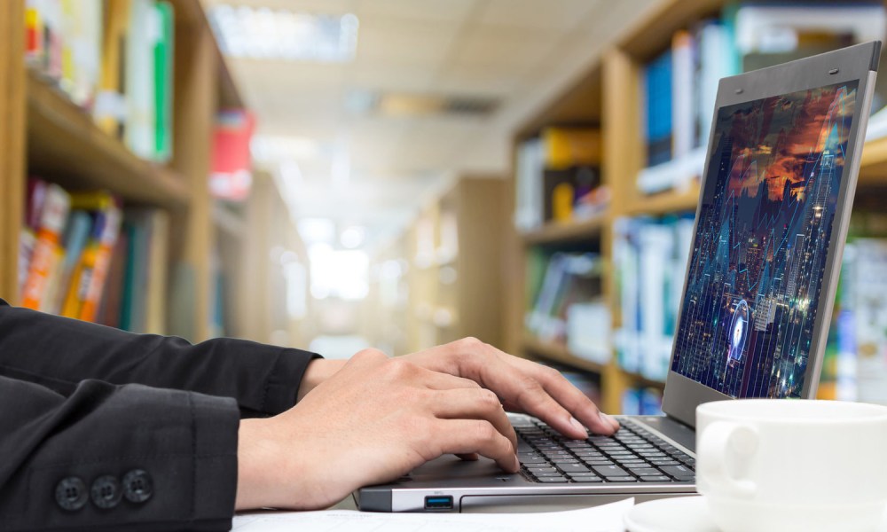 Man in suit jacket using computer in library.