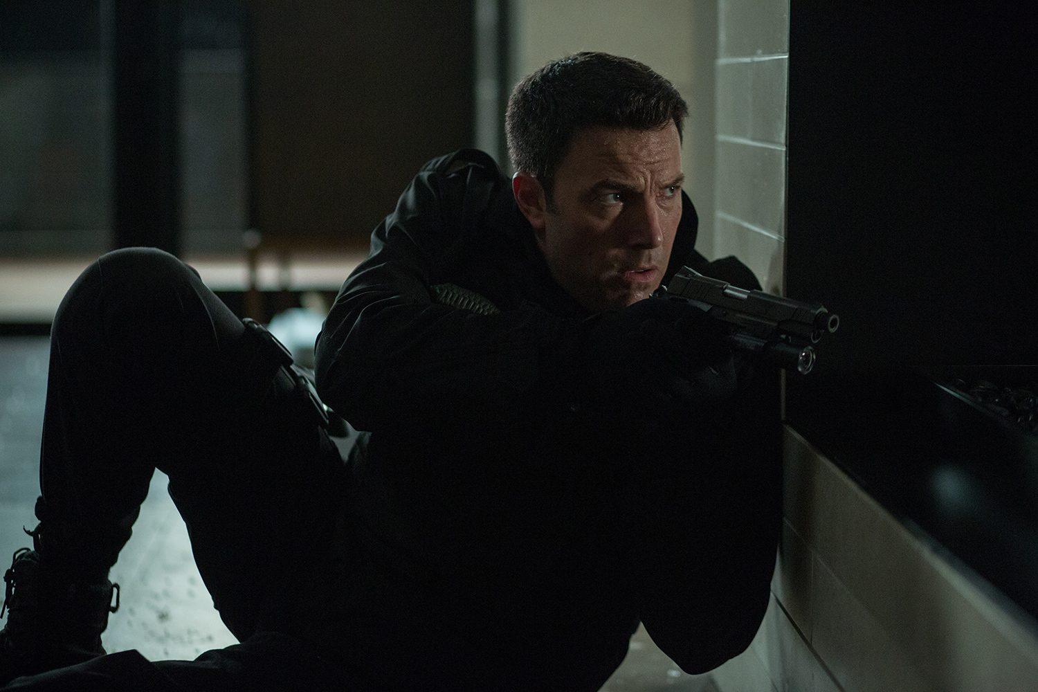 Ben Affleck se agacha y sostiene un arma en The Accountant.