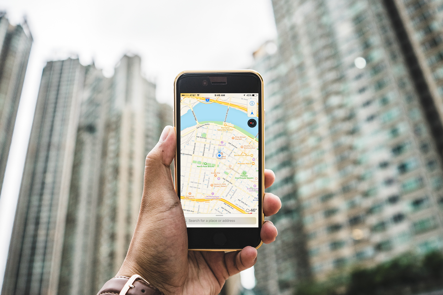 Personnel tenant un iPhone devant un paysage urbain avec Apple Maps.