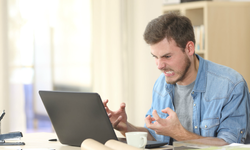 A person expressing angry emotion at a computer.