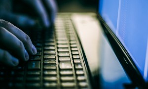 Close-up of hands on a laptop keyboard in a dark room.