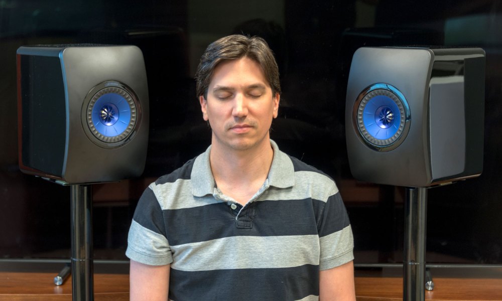 Man listening to KEF LS50 speakers with eyes closed.