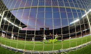 A soccer goal net with the rest of the pitch in front.