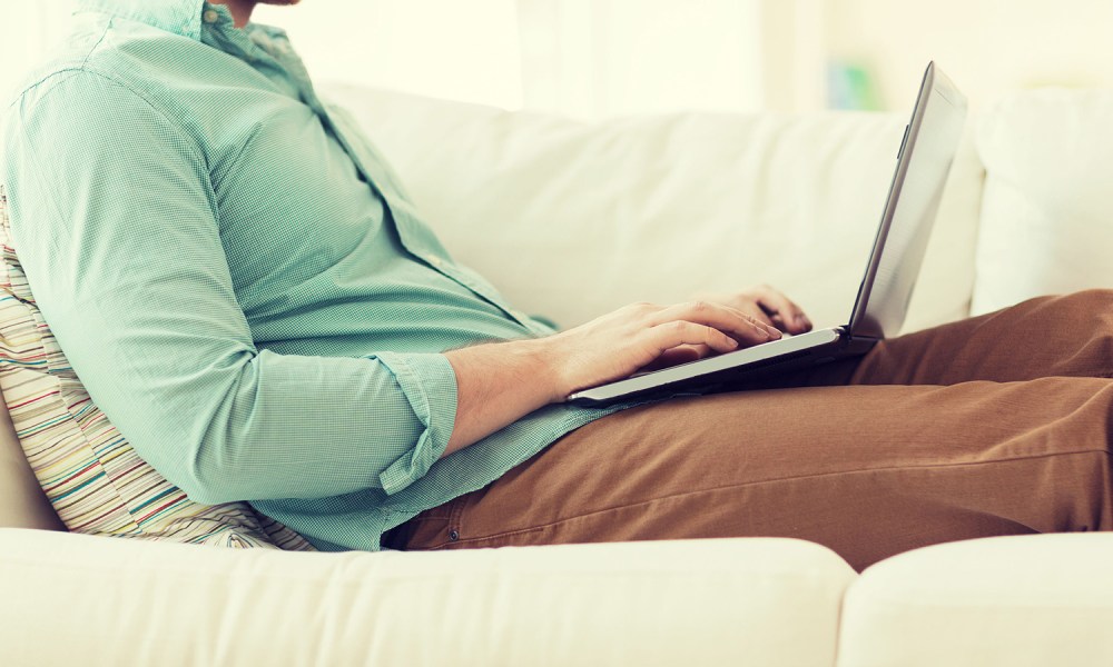 A person using a laptop while lounging on a couch.