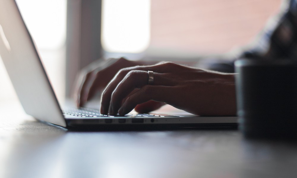 A close up of a person's hands typing on a laptop.