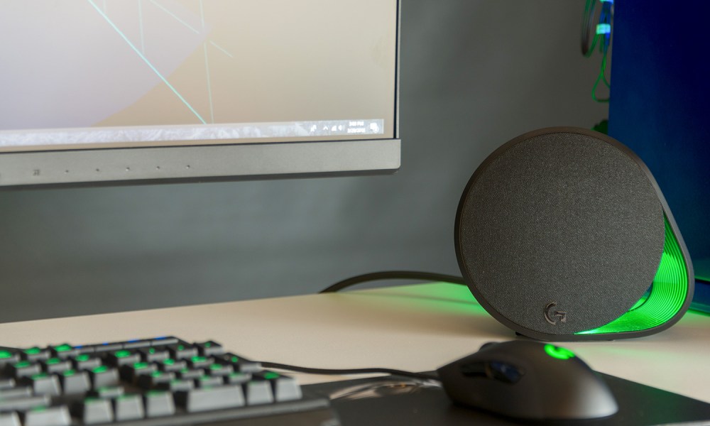 A Logitech speaker sitting beside a desktop computer.