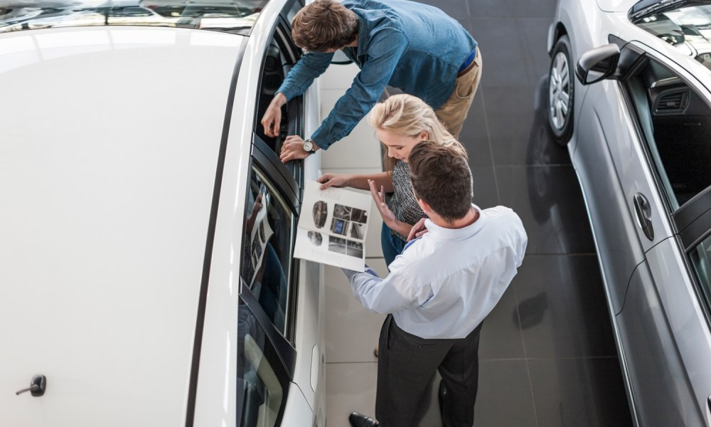 road rave subscription direct sales threaten traditional car dealers dealer showing brochure to young couple in showroom