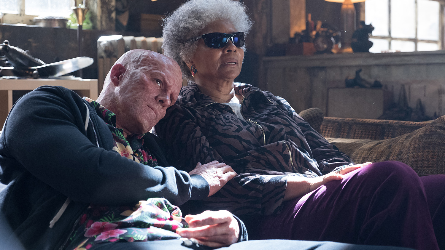Ryan Reynolds and Leslie Uggams as Deadpool and Blind Al sitting on a couch with Deadpool leaning his head on Al's shoulder in Deadpool 2.