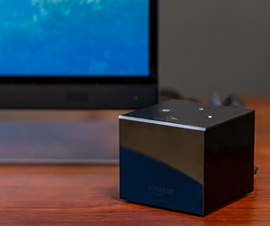 Amazon Fire TV Cube on a table with a TV in the background. 