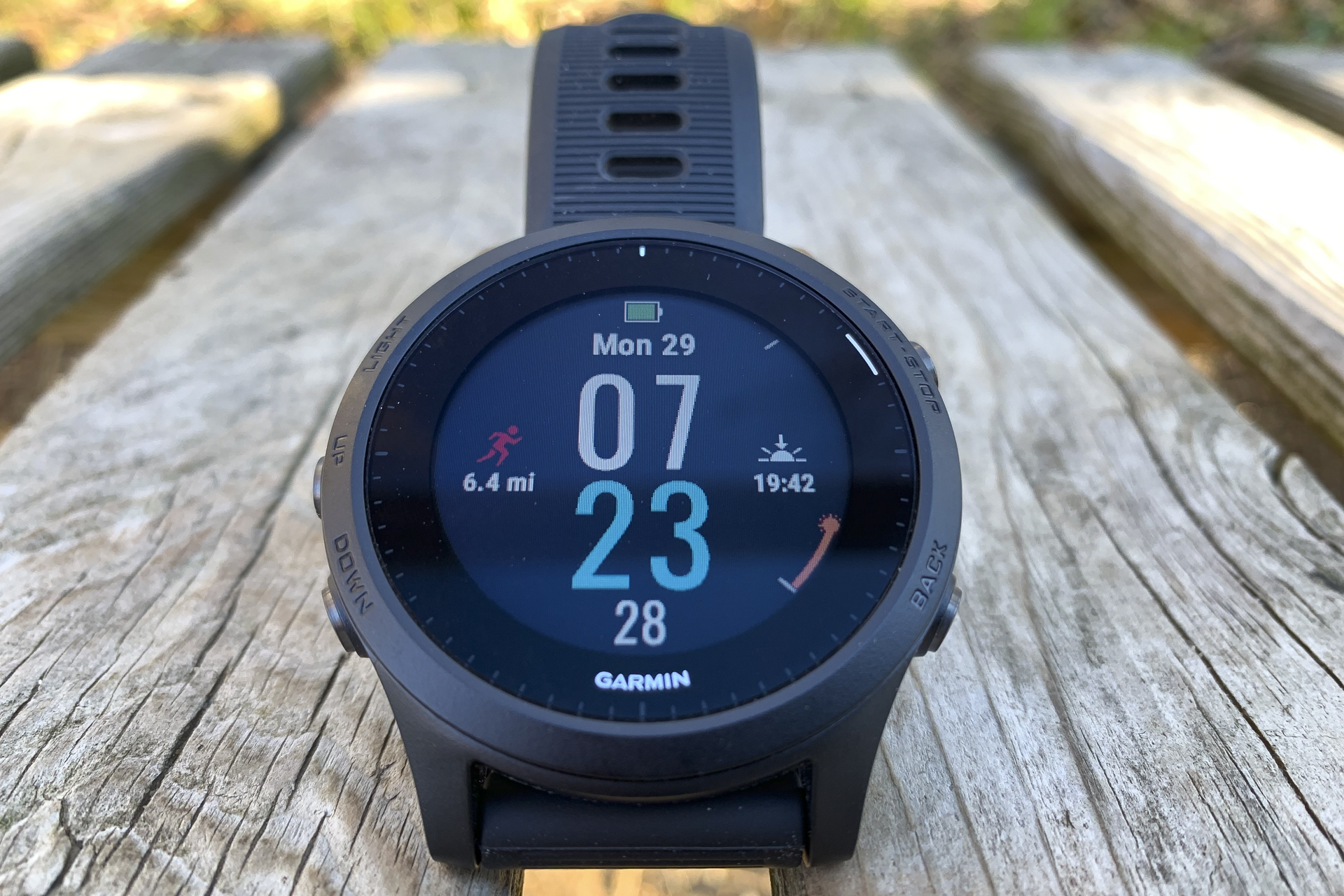 Умные часы Garmin Forerunner 945 размещены на деревянной поверхности с активным дисплеем.