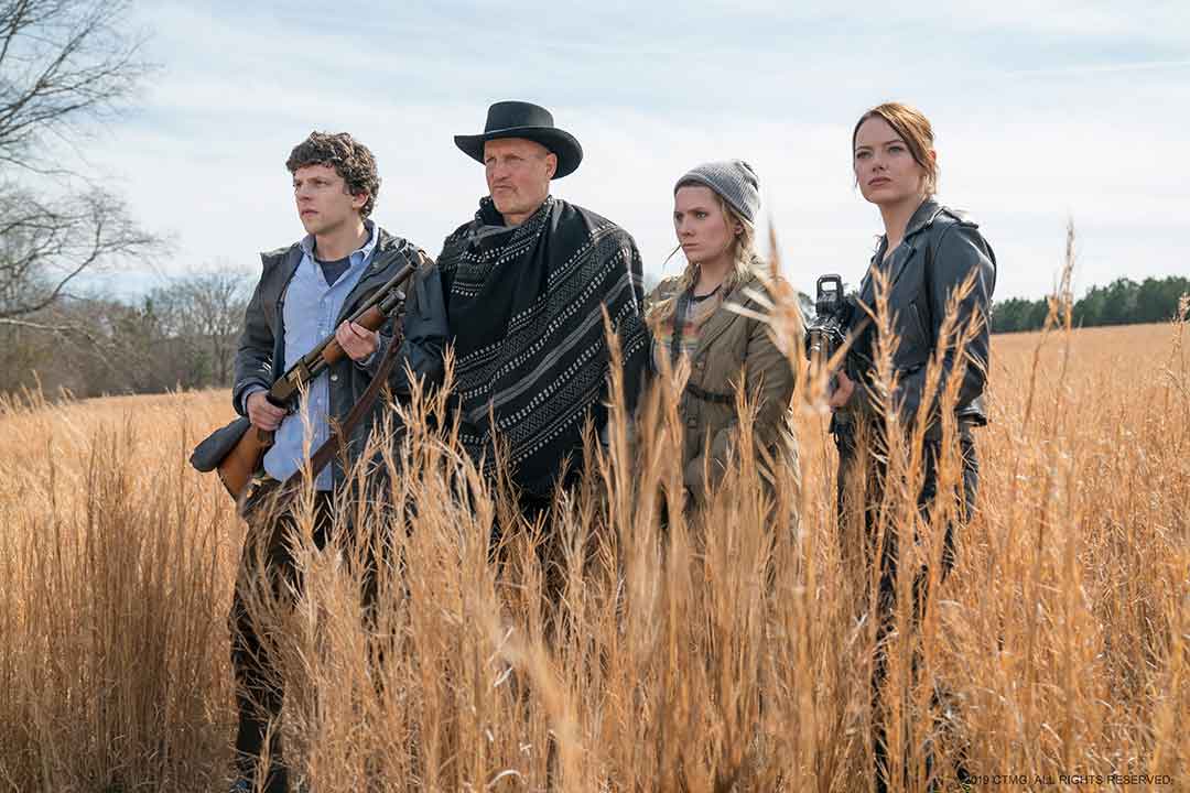 Jesse Eisenberg, Woody Harrelson, Abigail Breslin, and Emma Stone as Columbus, Tallahasse, Little Rock, and Wichita looking ahead while standing in a field of wheat in Zombieland: Double Tap.