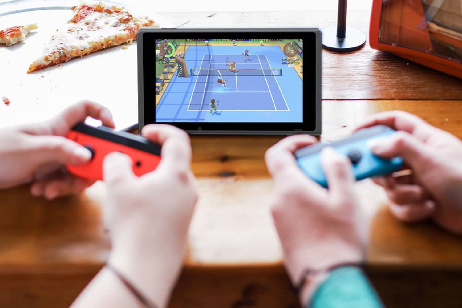 Two people playing Nintendo Switch which is placed on a table.