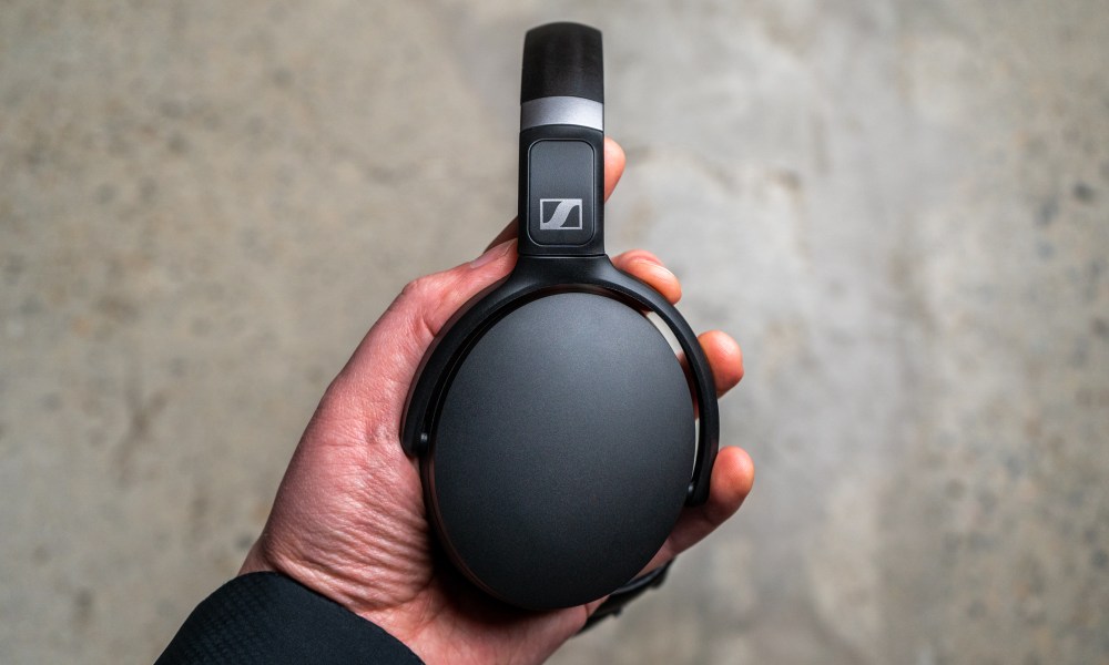 Holding the Sennheiser HD 450BT headphones.