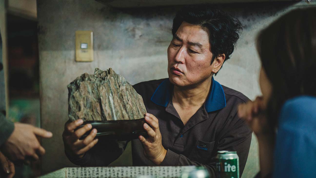 A man holding up a rock in Parasite.