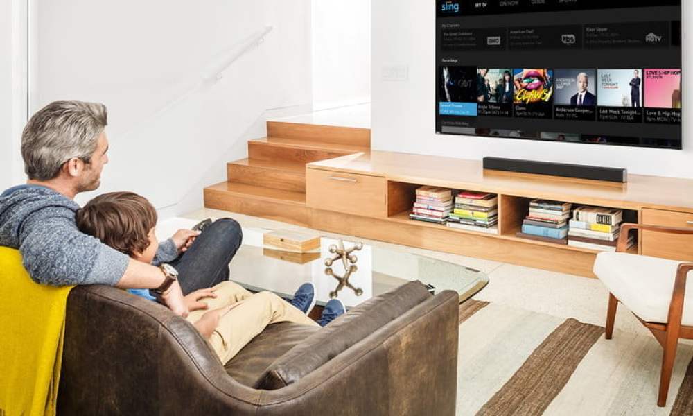 A man watching Sling TV in his living room.