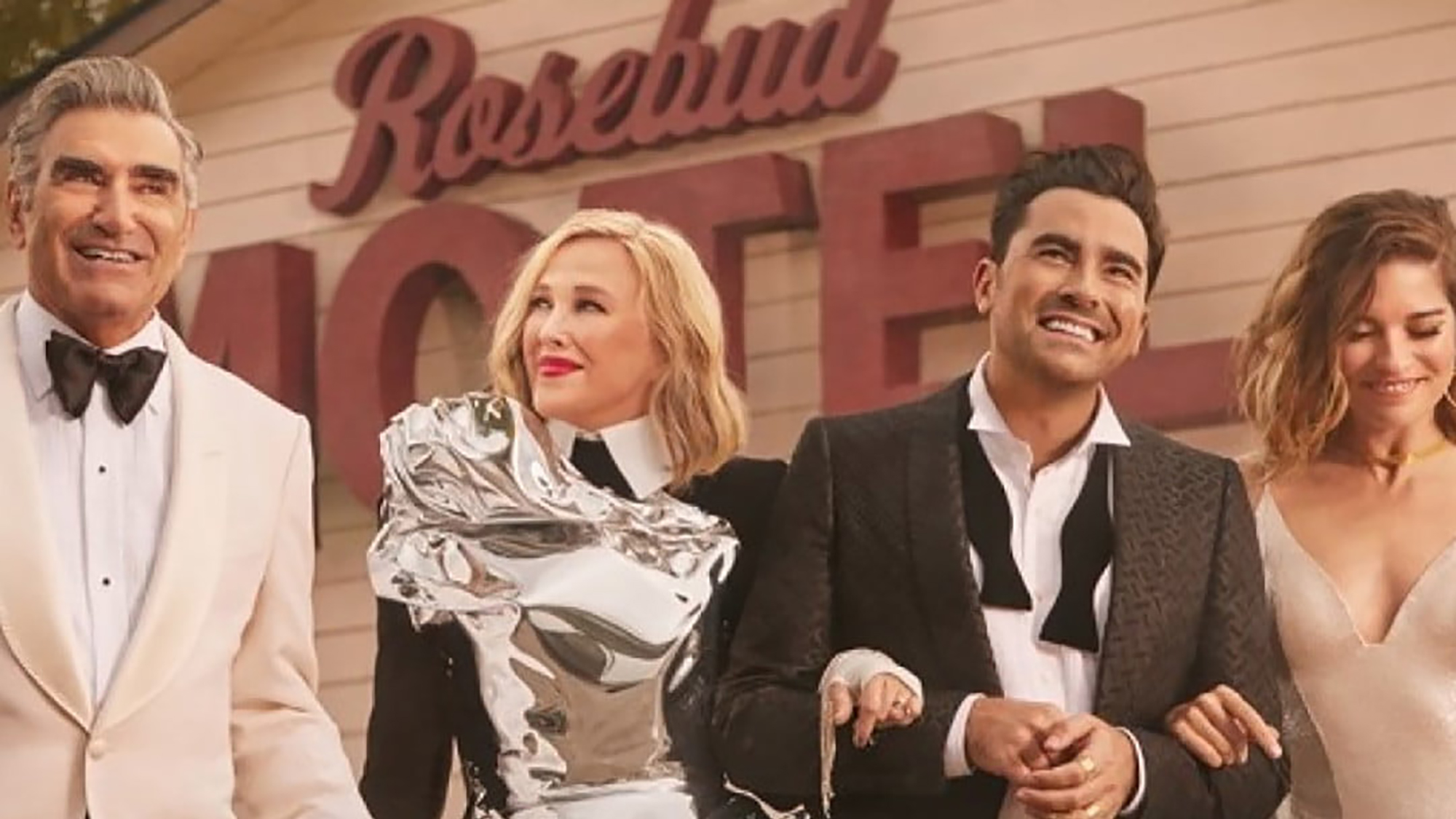 The four Rose family members with arms linked in a scene from Schitt's Creek.