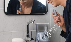 man using waterpik water flosser