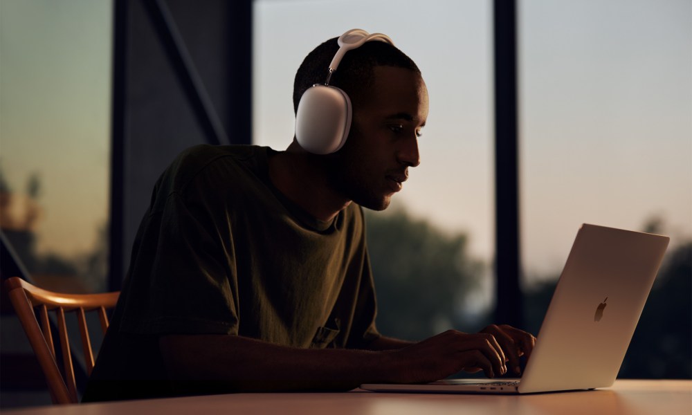 A MacBook user wearing Apple AirPods Max headphones.