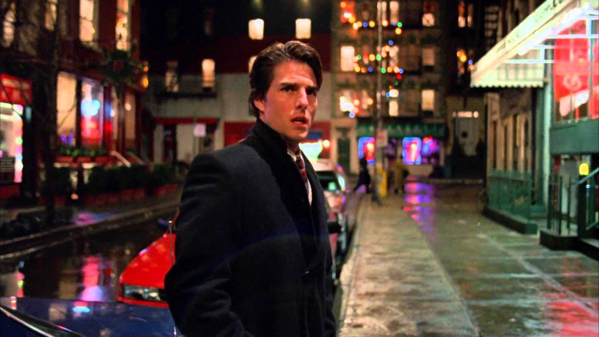 Tom Cruise como Bill Harford parado em uma rua à noite no filme De Olhos Bem Fechados.