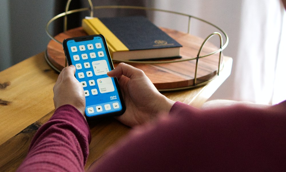 Person holding iPhone 11 with a customized home screen layout.