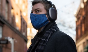 A man wears Apple AirPods Max headphones on a city street.