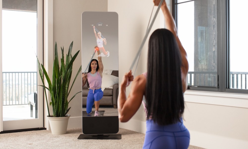 A woman ecercising in front of the Proform Vue, looking at an imbedded ddigital screen in the mirror's reflection.