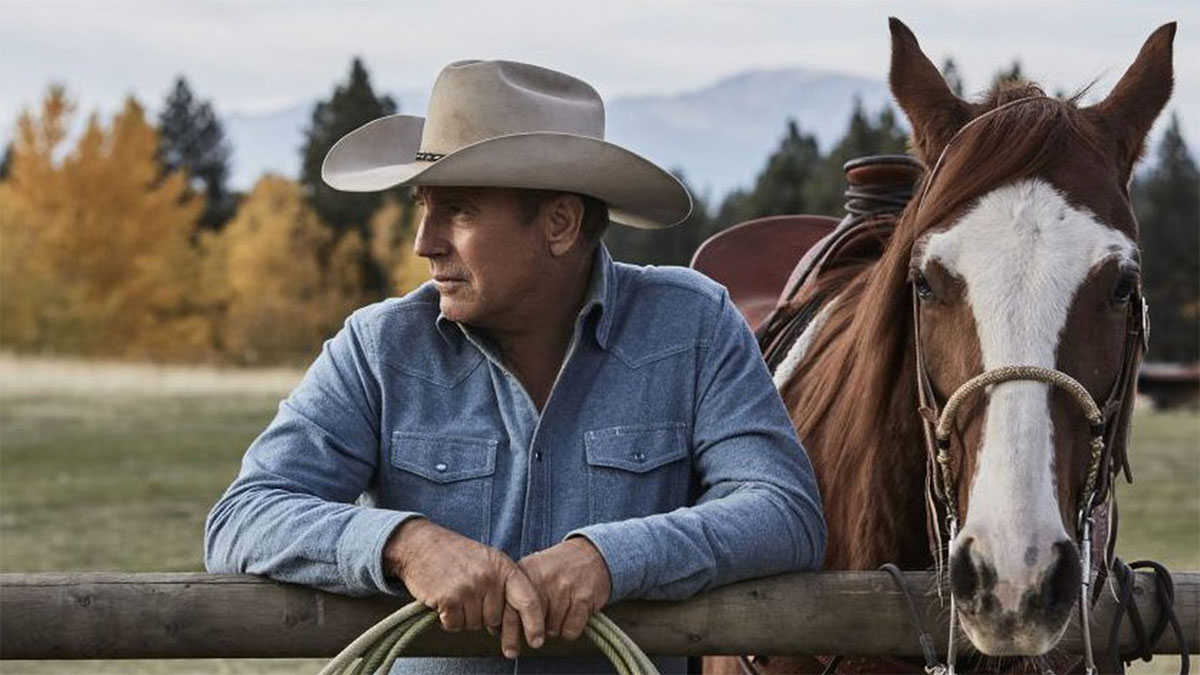 Kevin Costner à Yellowstone debout à côté d'un cheval.