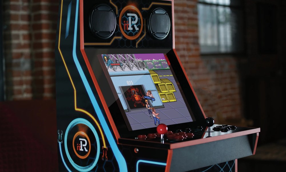 An iiRcade arcade cabinet standing against a brick wall.