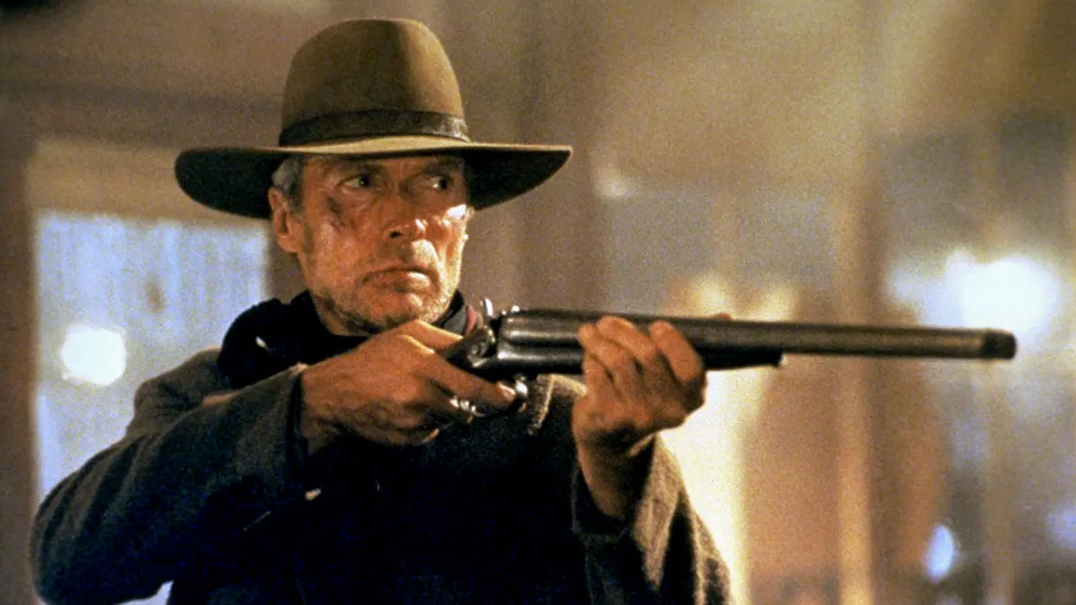 Clint Eastwood como William Munny apuntando con su rifle a alguien fuera de cámara en Sin perdón.