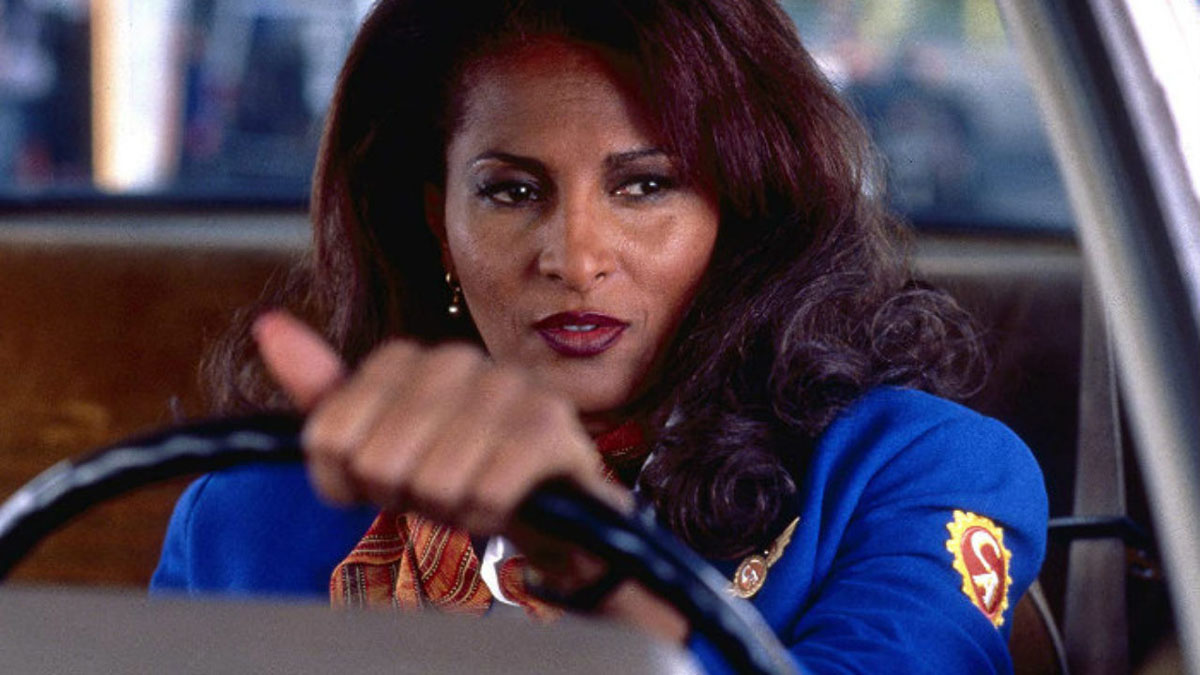 Pam Grier como Jackie Brown ao volante de um carro em Jackie Brown.