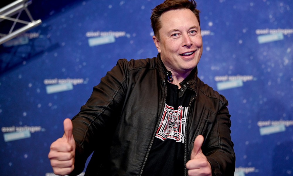 Elon Musk holding two thumbs up.