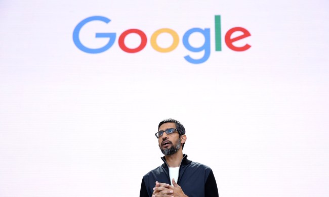 Sundar Pichai stands in front of a screen showing the Google logo.