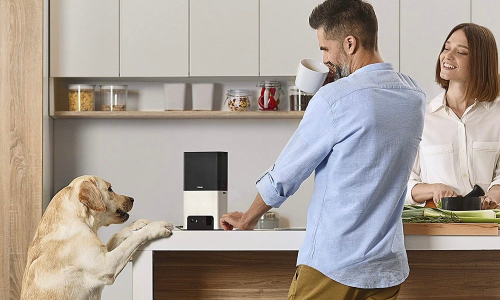 A dog and his human companions surrounding the Petcube Bites 2.