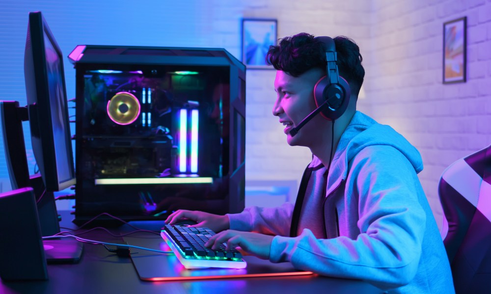 A man playing games on the computer, wearing a headset.