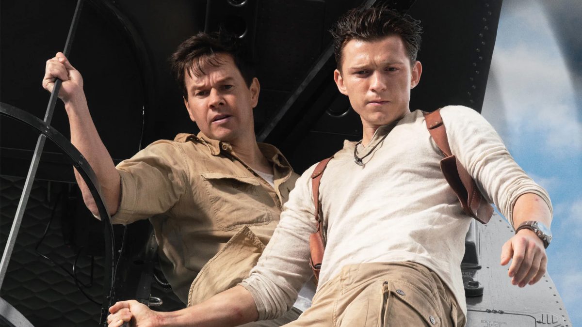 Tom Holland e Mark Wahlberg estão na beira de um avião olhando para baixo.