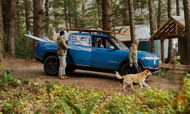 People and a dog standing in front of a Rivian R1T electric pickup truck.