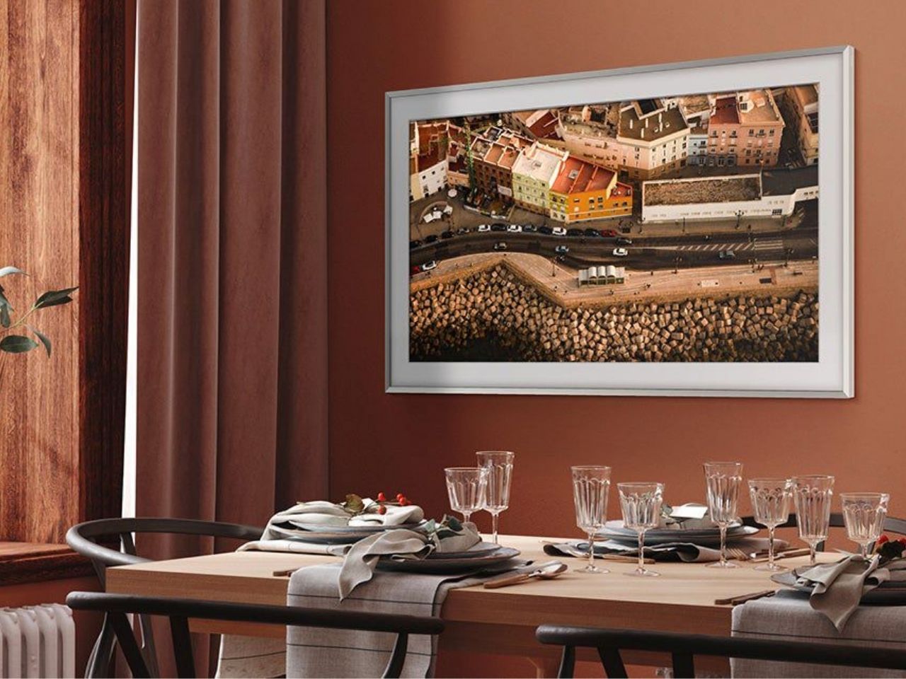 Uma TV Samsung The Frame 4K de 55 polegadas está pendurada na parede de uma sala de jantar.