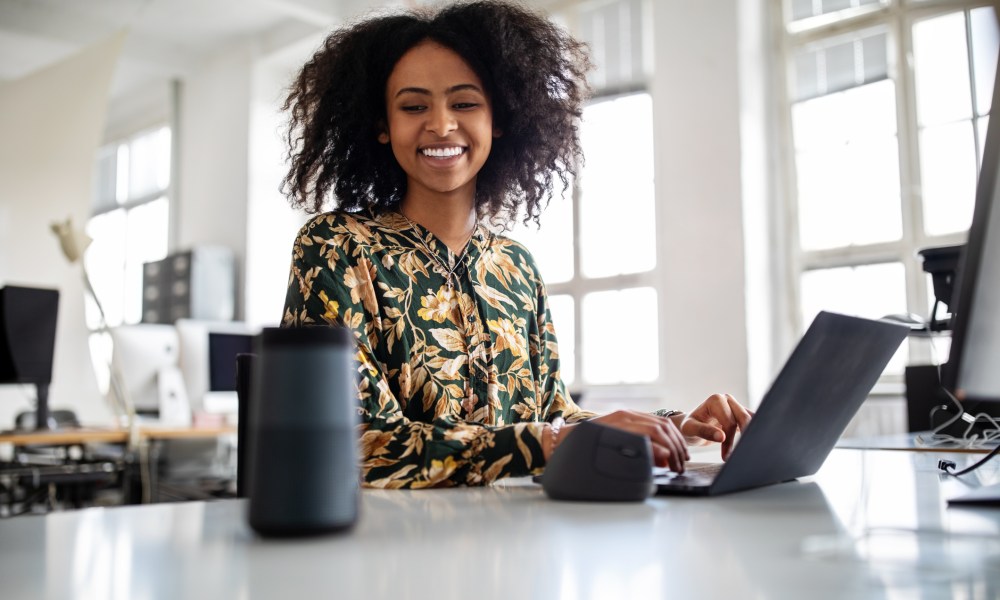 Woman using smart speaker while working in office.