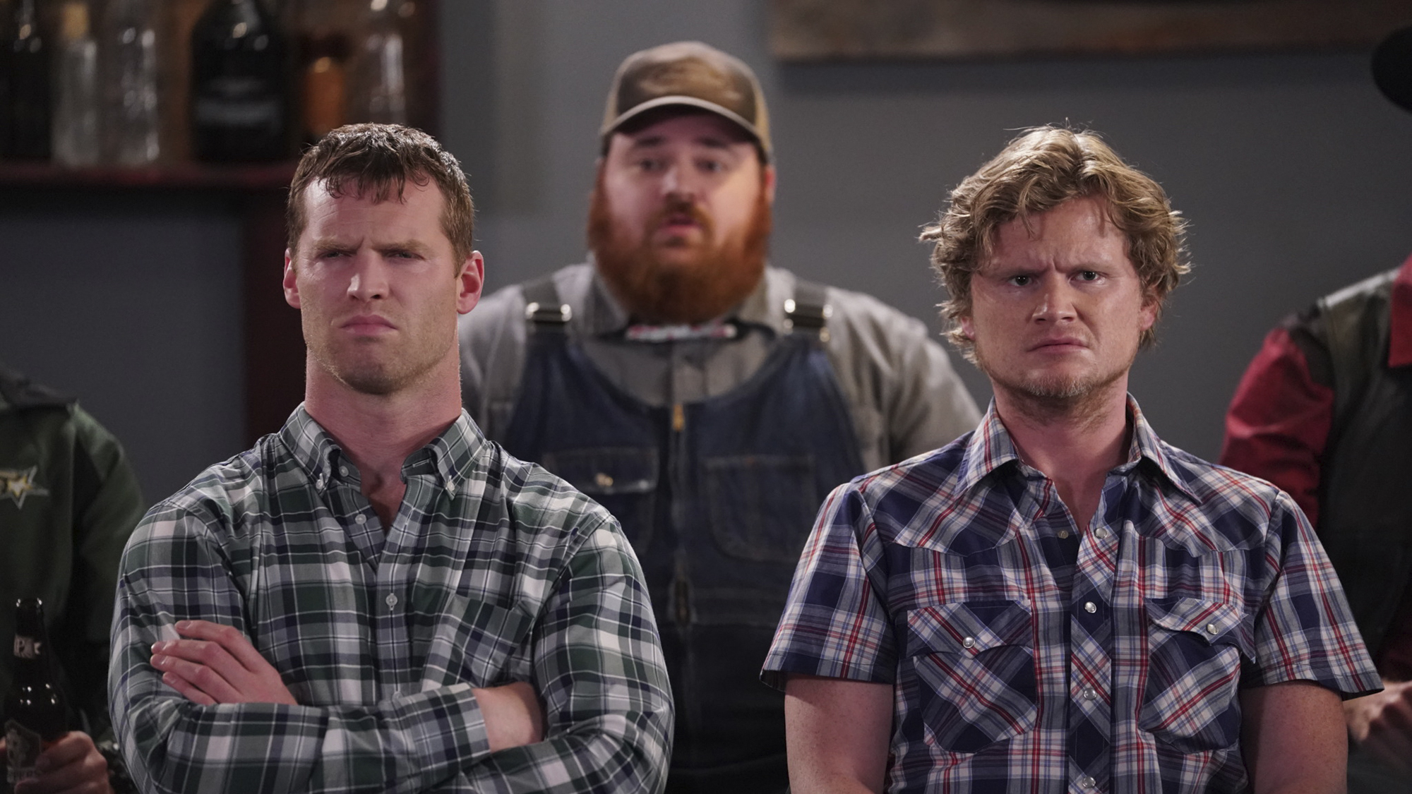 Trois personnages principaux de Letterkenny debout ensemble, portant des carreaux et une salopette.