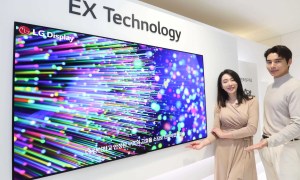 Models stand beside a demo of LG Display's OLED EX panel.