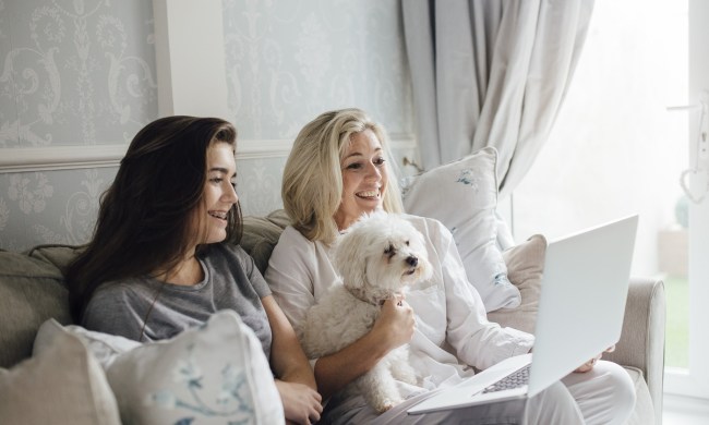 Two women video calling on their laptop with dog nearby protected by McAfee.