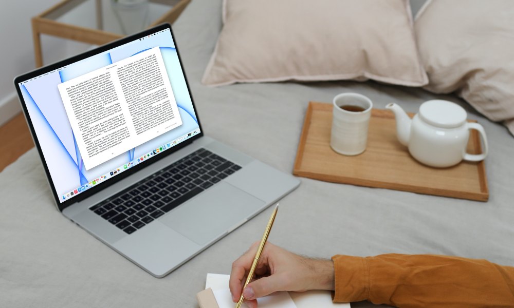 Open book on a MacBook in bed.