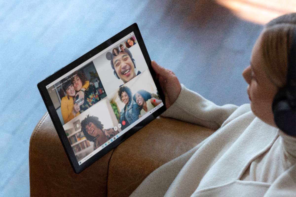 Someone sitting and holding a Microsoft Surface Pro 7 while taking a video call.